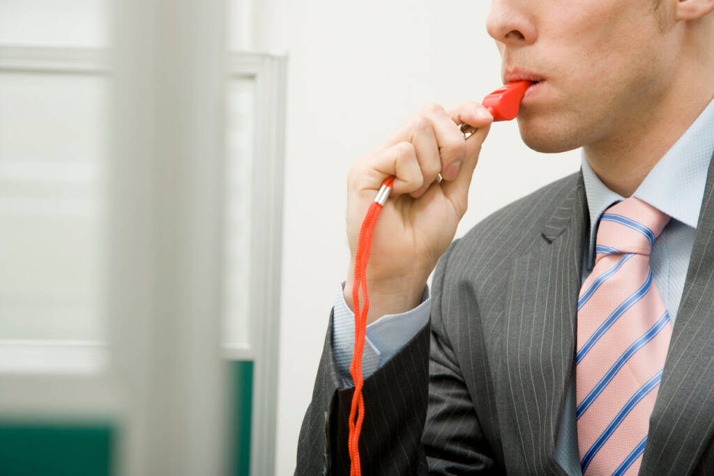 man in a suit blowing a red whistle