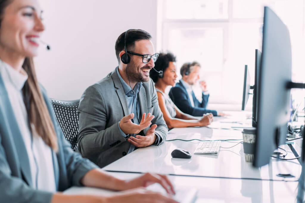 four client service reps working with headsets on at computers.