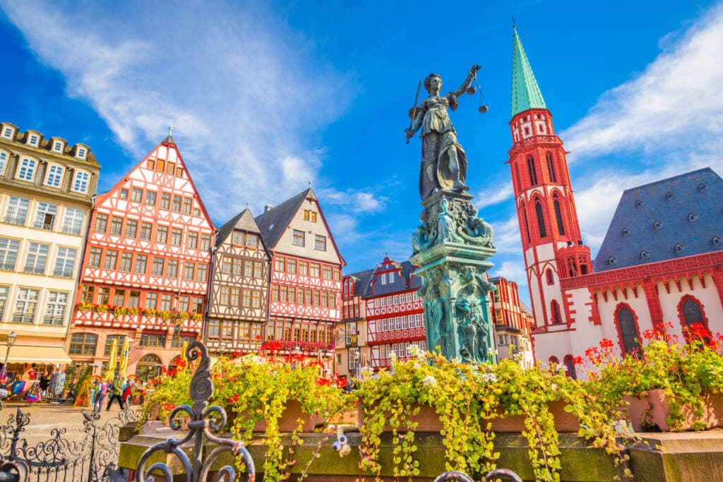 Historic Frankfurt town square with half-timbered buildings, statue, and red church tower.